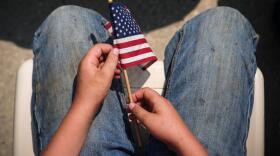 Someone holds an American flag as President Trump speaks at Burning Hills Amphitheatre during the Theodore Roosevelt Presidential Library opening ceremony, Wednesday, July 1, 2026, in Medora, N.D. (Julia Demaree Nikhinson/AP)