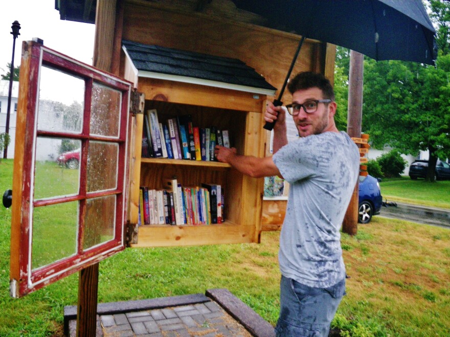 Ryan Ireland restocks a Little Free Library on a rainy day in Clifton.