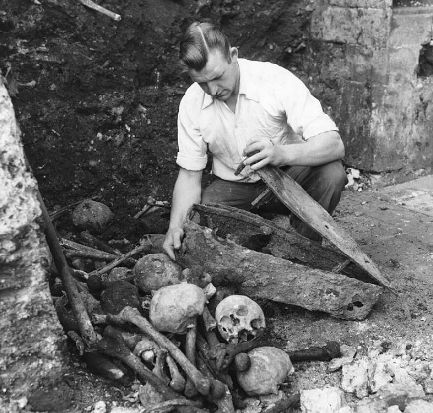 A worker opens the coffin of a baby in a churchyard in London, where victims of the Black Death were buried in 1348.