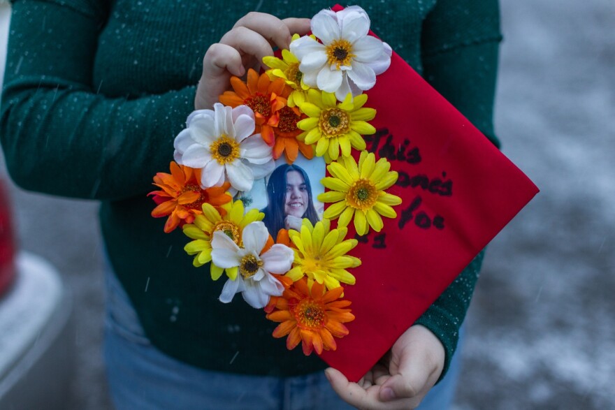 A person hold red a graduation cap decorated with a picture of teenage girl and flowers.