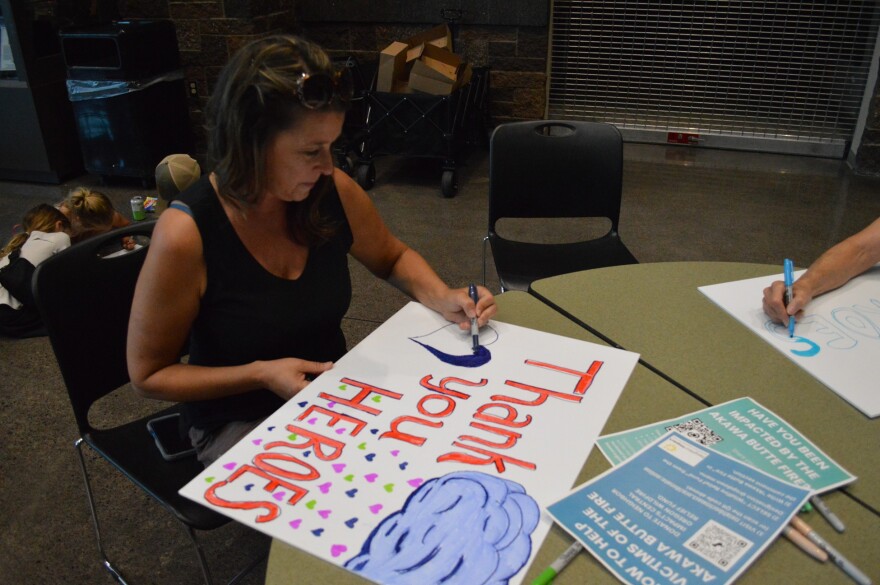A person makes a sign thanking firefighters and first responders working the Akawa Butte Fire during a public meeting at Sisters High School July 23, 2026.