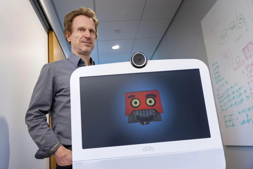 Professor Matthias Scheutz follows AVA along a hallway at the Human Robot Interaction Lab, at Tufts University.