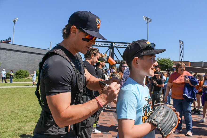Conor Weber, 12, gets an autograph from Banana Ball Firefighters team member Zachary Bridges on Thursday at Equity Bank Park.