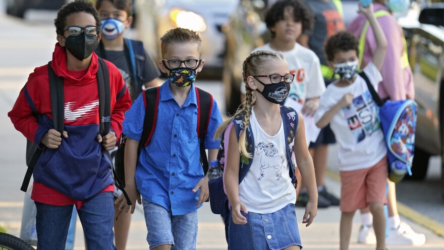 In this Tuesday, Aug. 10, 2021 file photo, Students, some wearing protective masks, arrive for the first day of school at Sessums Elementary School in Riverview, Fla.