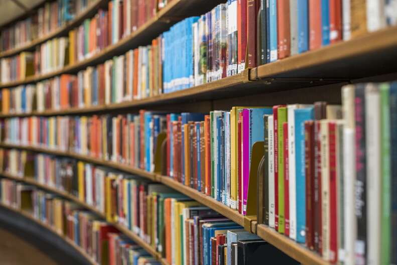 A wall of shelves filled with colorful books in a library.