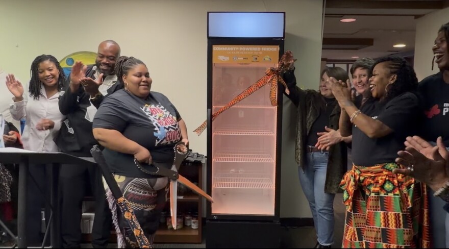 Melody McCurtis (center), Deputy Director of Metcalfe Park Community Bridges, cut the ribbon on a new community powered fridge at the organization's headquarters.