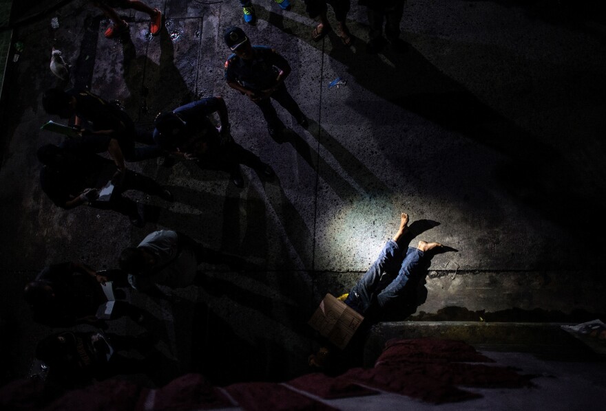 Police officers examine the body of an alleged drug dealer on a street in Manila in July, his face covered with packing tape and a placard that read, "I'm a pusher."