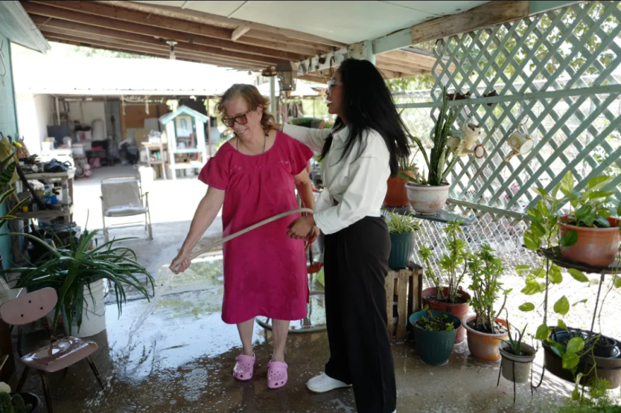 Maria Salinas cools her patio and waters her plants in Alto Bonito in Starr County while visiting with community leader Anabel Garza as temperatures hover around the 100-degree mark. Garza helps people in the Valley apply for energy assistance.