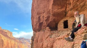 Two people sit along the wall of the Grand Canyon.