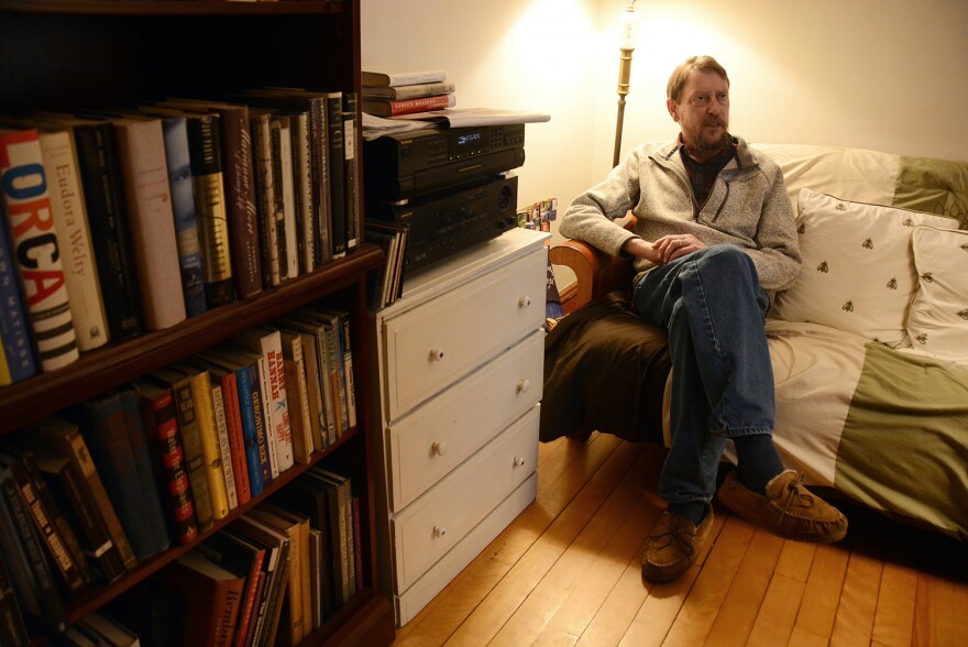 Author Jeffrey Lent sits on a couch near a bookshelf