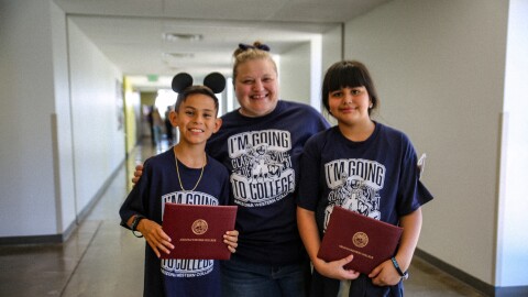 Desert View Academy teacher Jenny Ballou smiles alongside her students, Damian and Alexis.