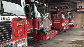 A row of parked fire engines in a garage.