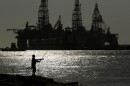 FILE - A man fishes near docked oil drilling platforms May 8, 2020, in Port Aransas, Texas. 