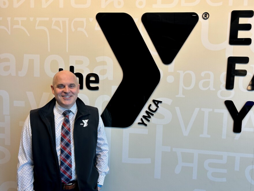 A man stands in front of a sign for a YMCA
