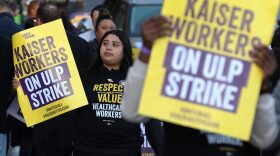 Striking Kaiser Permanente workers hold signs as they march in front of the Kaiser Permanente San Francisco Medical Center in San Francisco, California.