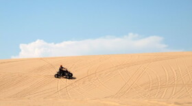 A man rides an ATV across the sand at Beaver Dunes, a former state park recently acquired by the City of Beaver.