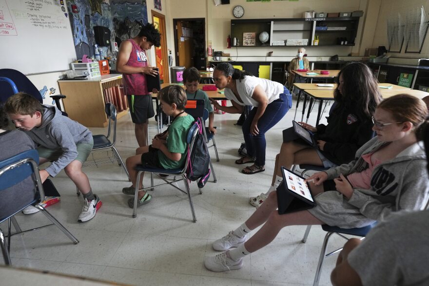 Art teacher Lindsay Johnson, center, has students explore how to use generative AI features in Canva at Roosevelt Middle School, Wednesday, June 25, 2025, in River Forest, Ill. (AP Photo/Nam Y. Huh)