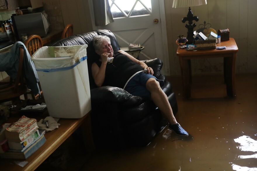 Elsie Lazarus is overcome with emotion Thursday as she sits in her flooded living room while retrieving what she can from her home in St. Amant, La.