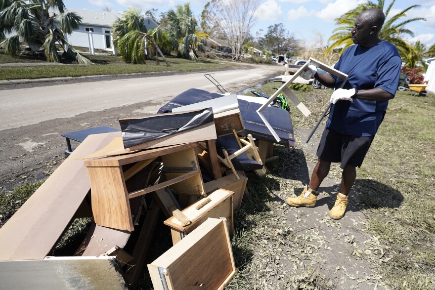 Andre McCourt throws away water logged furniture from his home Tuesday, Oct. 4, 2022, in North Port, Fla. Residents were cleaning up flooding damage after Hurricane Ian came ashore last week. (AP Photo/Chris O'Meara)