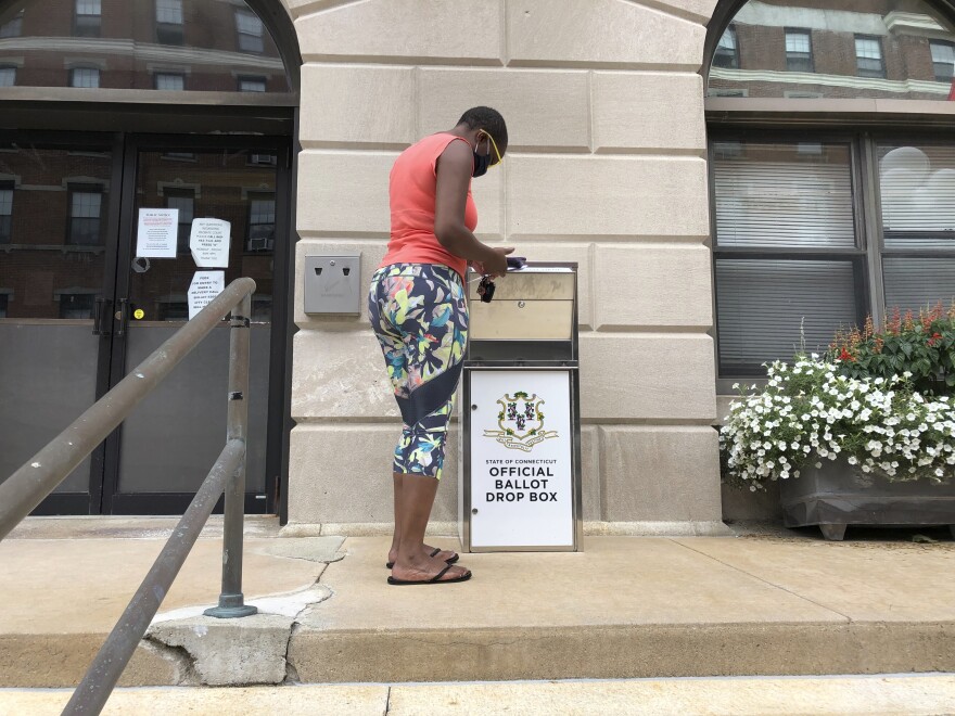 Katrina McKelvin of New London, Conn. on Aug. 6, 2020 deposits her absentee ballot for the Aug. 11 primary in a special box that has been set up outside the New London City Hall. 