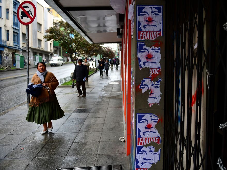 A woman walks past posters depicting Bolivian ex-President Evo Morales as a clown and a fraud in La Paz on Monday.