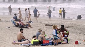 People enjoy a day out on Sunday in Huntington Beach, Calif. High numbers of beachgoers over the weekend prompted warnings from officials that defying stay-at-home orders could reverse progress and bring the coronavirus surging back.