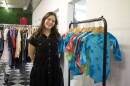 A woman stands next to a rack of clothes in a room with white and black tiled floor