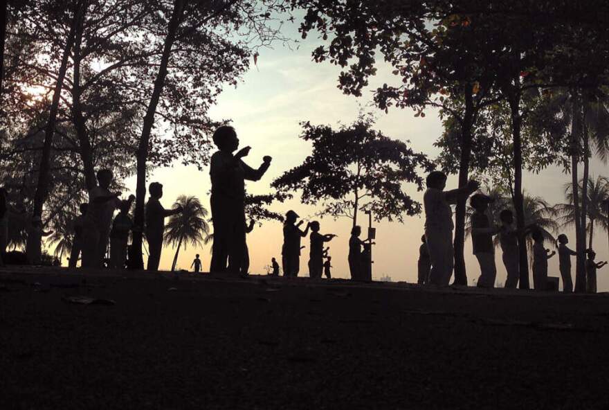Elderly people are silhouetted as they exercise early in the morning on Tuesday Oct. 29, 2013, by the beach, in Singapore. (Wong Maye-E/AP)