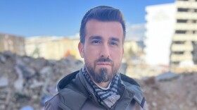 Ali Kafadenk, 34, poses in front of the rubble of his destroyed apartment in Islahiye, Turkey. He and his wife Merve, 27, survived the earthquake that struck Turkey and Syria on Feb 6.