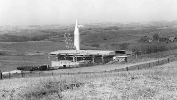 Old black and white image of a missile sitting in a field.