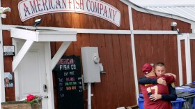A man hugs a police officer in front of the American Fish Company following a fatal shooting that occurred the night before, Sunday, Sept. 28, 2025, in Southport, N.C.