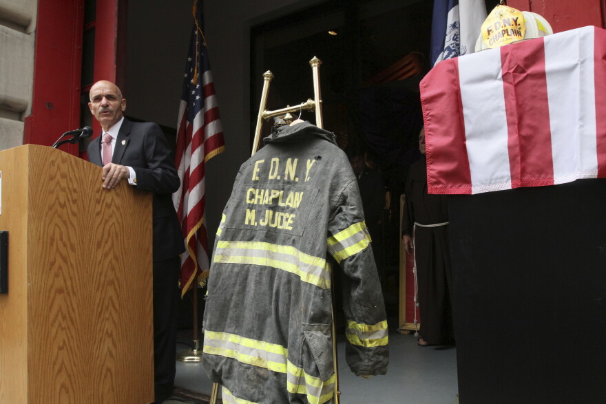  In this Sunday Sept. 11, 2011 file photo, the bunker coat and helmet worn by FDNY Chaplain Mychal Judge are displayed as City of New York Fire Commissioner Salvatore J. Cassano speaks at the New York City Fire Museum in New York during a memorial ceremony for the 343 members of the FDNY who lost their lives in the World Trade Center attacks. The bunker coat and helmet worn by Father Judge on Sept. 11, 2001, were dedicated to the museum during the service. (AP Photo/Tina Fineberg, File)