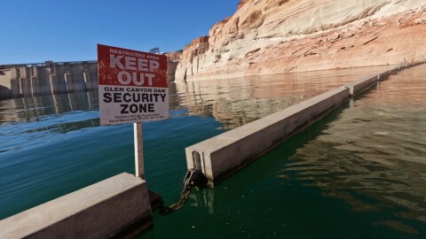 A sign reading "keep out" is displayed just upstream of Glen Canyon Dam at Lake Powell, June 8, 2022, in Page, Ariz.