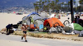 A jogger runs past a homeless encampment in the Venice Beach section of Los Angeles on June 8, 2021.