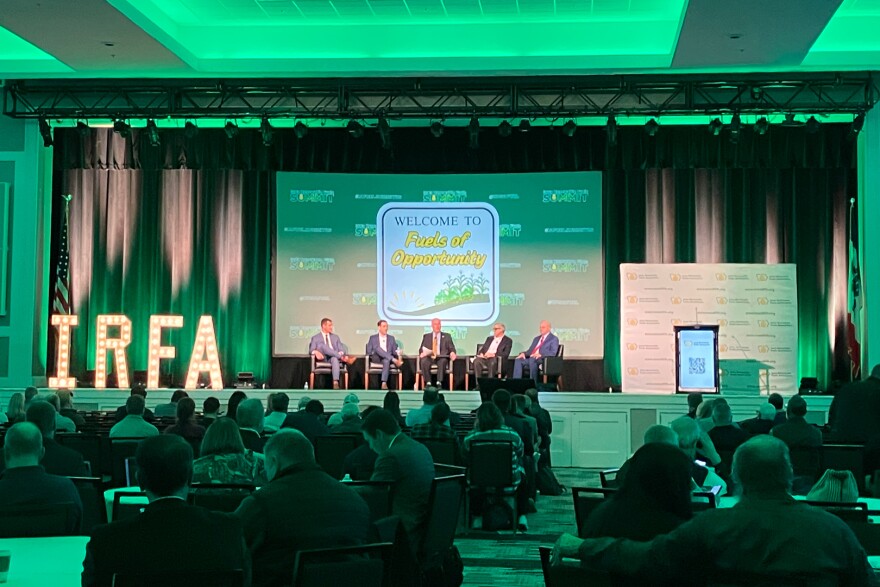 Five men sit on a stage with a screen behind them that reads: Welcome to Fuels of Opportunity.