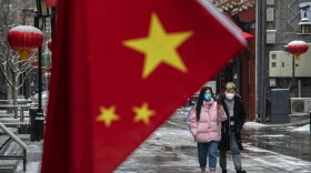 A Chinese couple wear protective masks as they walk during a snowfall in an empty and shuttered commercial street on February 5, 2020 in Beijing, China. (Kevin Frayer/Getty Images)