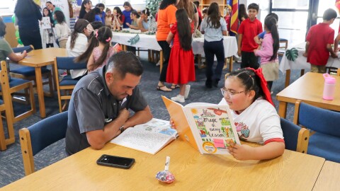 Smiling, Makayla read her book along with her parent at McGraw's special book signing .
