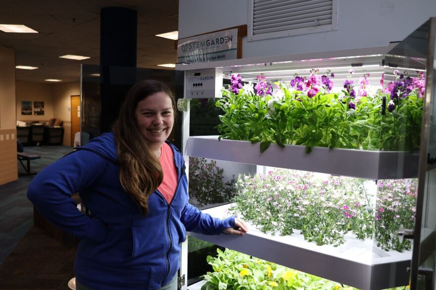 A lady poses beside a hydroponic growing setup