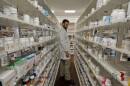Pharmacy Technician amongst two shelves of prescription pills.