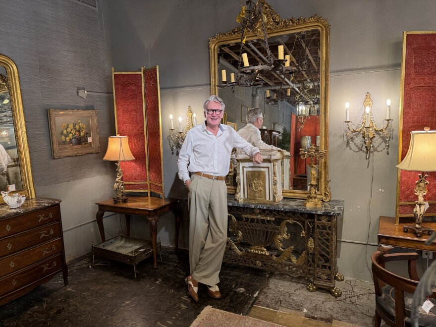 Antique store owner Michael Millard-Lowe stands around furniture inside his Norfolk showroom.