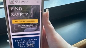 A hand holding a phone that shows the Simply Report app on it.