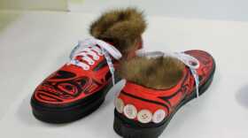 The same pair of red shoes, with one turned around to show buttons sewed across the heel