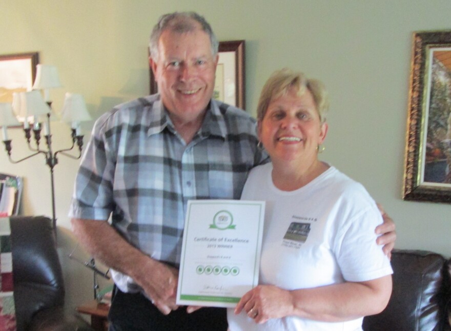 The beached whale in Newfoundland has been a blessing for Tom and Doris Sheppard's local business. Here, they hold a 5-star review of their B&B from TripAdvisor.