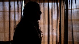 A woman we're referring to as "A" sits in her living room. Her identity is being protected because she is undocumented.