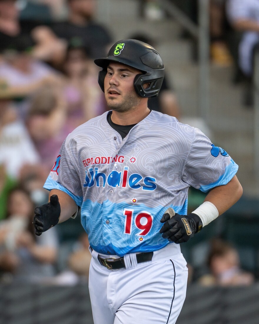 Running baseball player with exploding whales jersey.