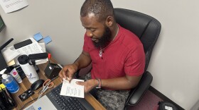 Image, brown skinned man putting picture into passport holder.