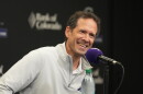 Paul DePodesta speaks into a purple microphone.