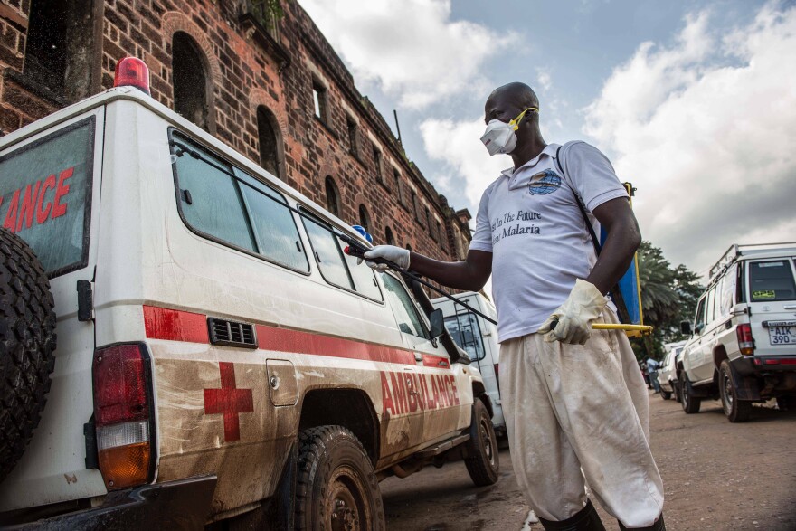 At the main ambulance base in central Freetown, Sierra Leone, a government health worker disinfects ambulances with chlorine spray during the 2014 Ebola outbreak.