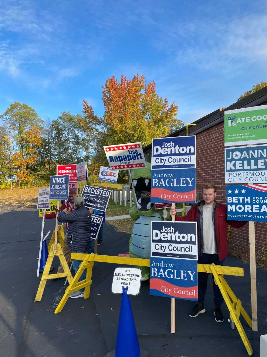 A group of campaigners hold vertical rows of signs for city council candidates outside Ward 3 in Portsmouth.