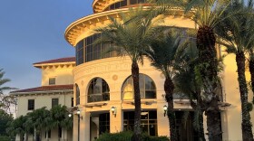 A rotunda flanked by palm trees at sunset, with University of South Florida on the exterior